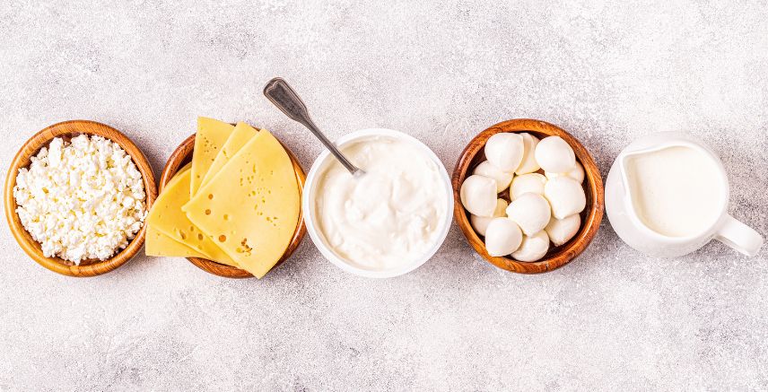 Small bowls of different kinds of cheese and milk.