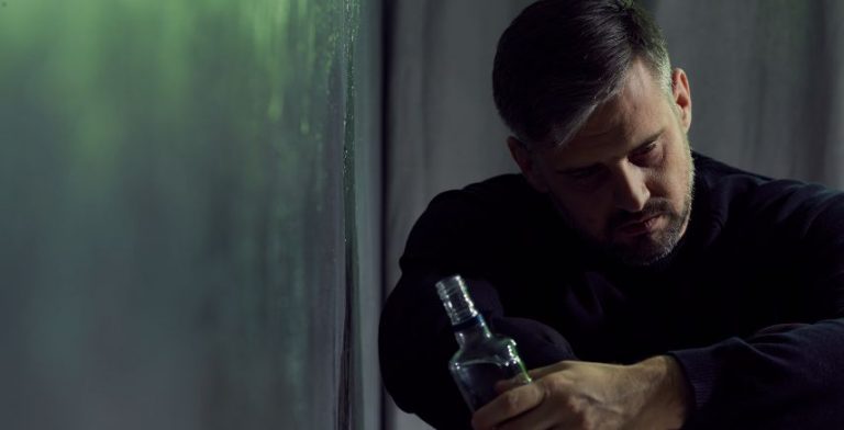 A man drinking by himself in a dark room