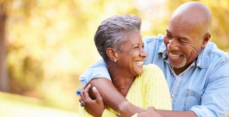 An older couple hugging each other outside.